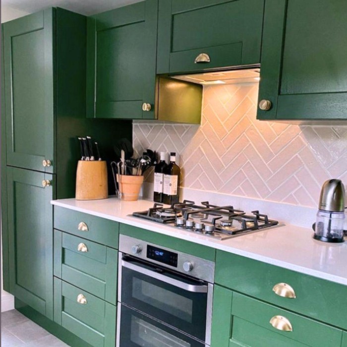 Herringbone effect pink Pewsey Vale wall tiles from Kennet collection in a green kitchen 1