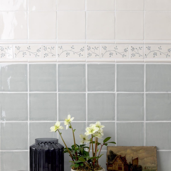 Wall of square tiled halfway with Emma flax blue pattern brick and taco tiles as a border, finished with half rounds.